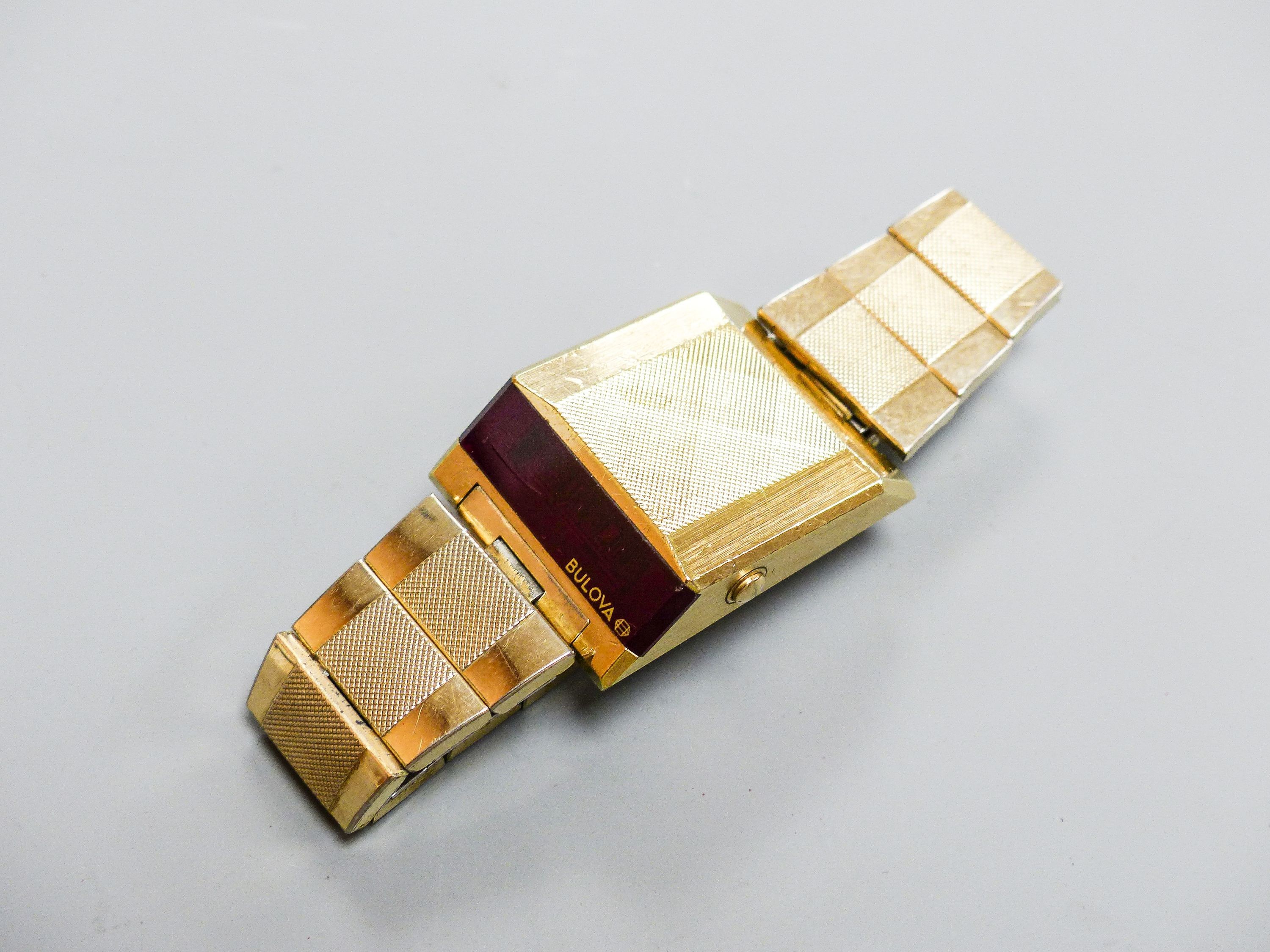 A gentleman's steel and gilt base metal Bulova digital wrist watch, on Bulova bracelet, case diameter 30mm (a.f.).